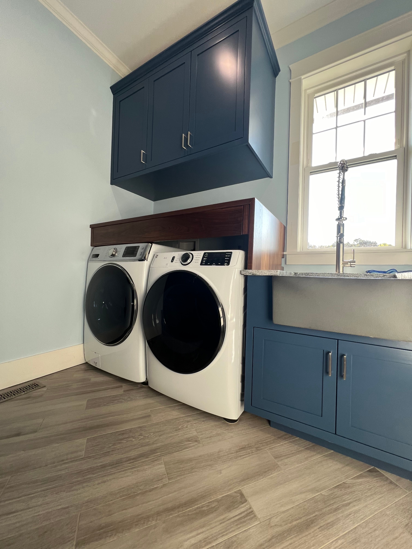 Custom laundry room with navy blue cabinets, butcher block countertop, and professional organization